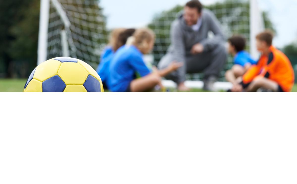 Voetbalcoach in gesprek met jonge voetballers